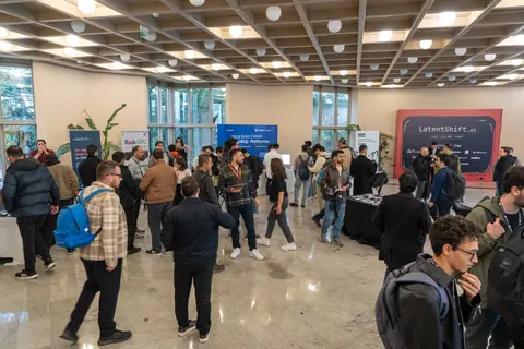 Attendees mingle around tables and banners in a bright foyer, beside a large LatentShift backdrop.