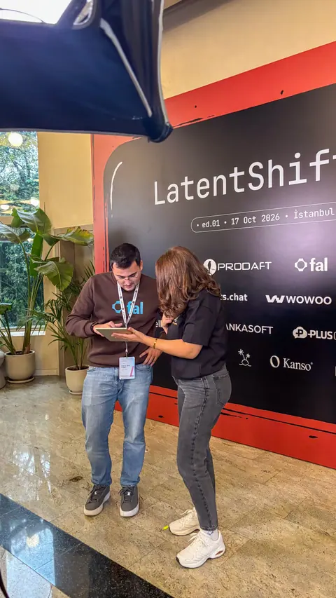 A man in a brown sweatshirt and a woman in a black shirt look down at a tablet beside the LatentShift backdrop.